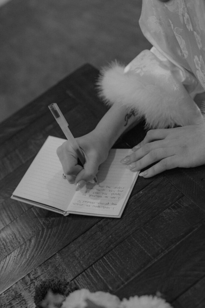 Bride writing her vows at her new hampshire airbnb on the morning of her Elopement in the white mountains