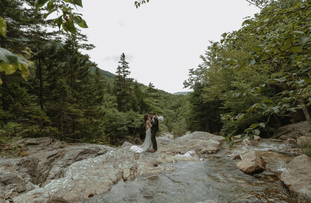New Hampshire Waterfall Elopement. Bride and Groom saying their vows at the top of a waterfall, surrounded by lush green trees