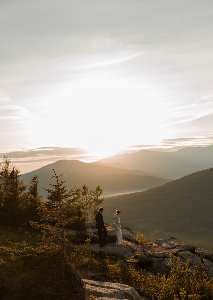 Bride and Groom watching the sunrise at the top of a mountain during their elopement in the White Mountains of New Hampshire