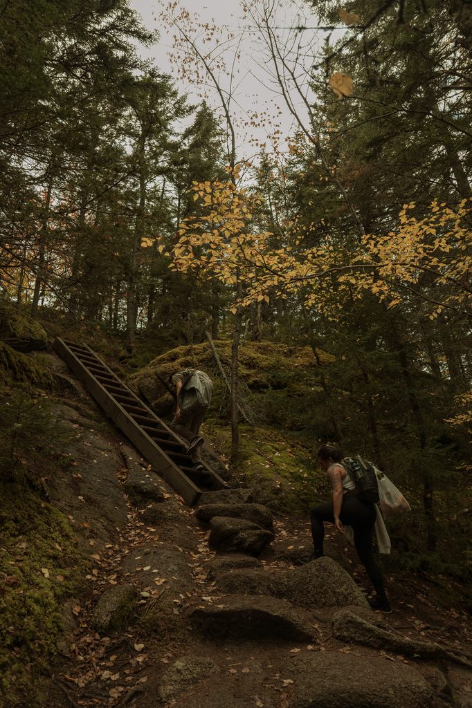 Couple exploring a mountain trail during their adventurous fall foliage elopement in New Hampshire